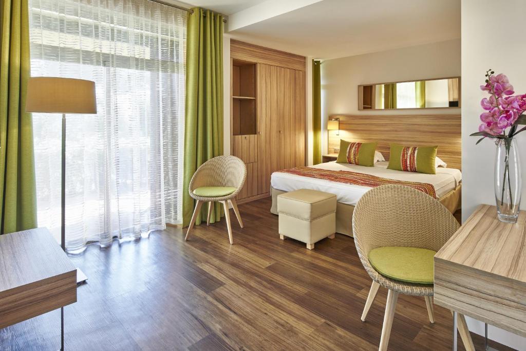 a hotel room with a bed and a table and chairs at Hôtel Vacances Bleues Delcloy in Saint-Jean-Cap-Ferrat