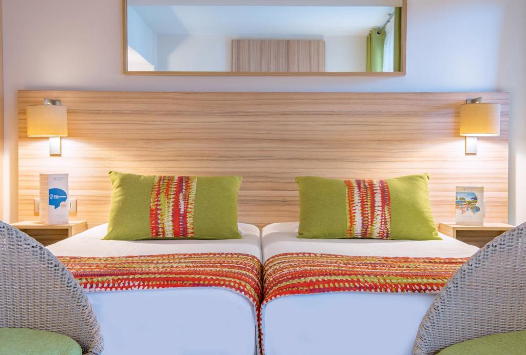 a hotel room with two beds and two chairs at Hôtel Vacances Bleues Delcloy in Saint-Jean-Cap-Ferrat