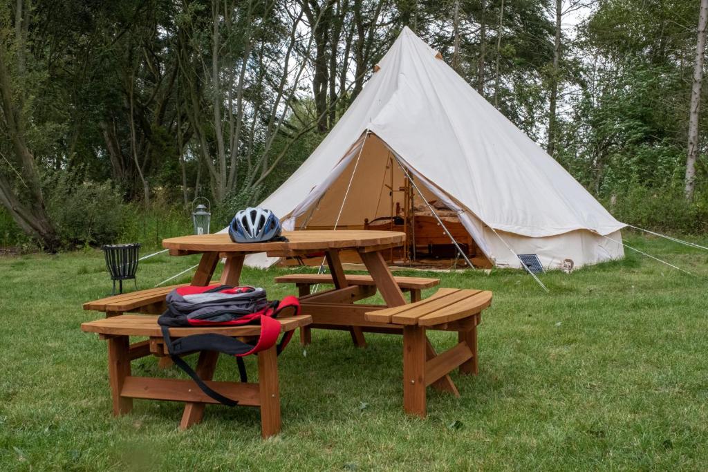 uma mesa de piquenique e uma tenda num campo em Sleeps-6 lakeside bell tent - Suffolk em Sudbury