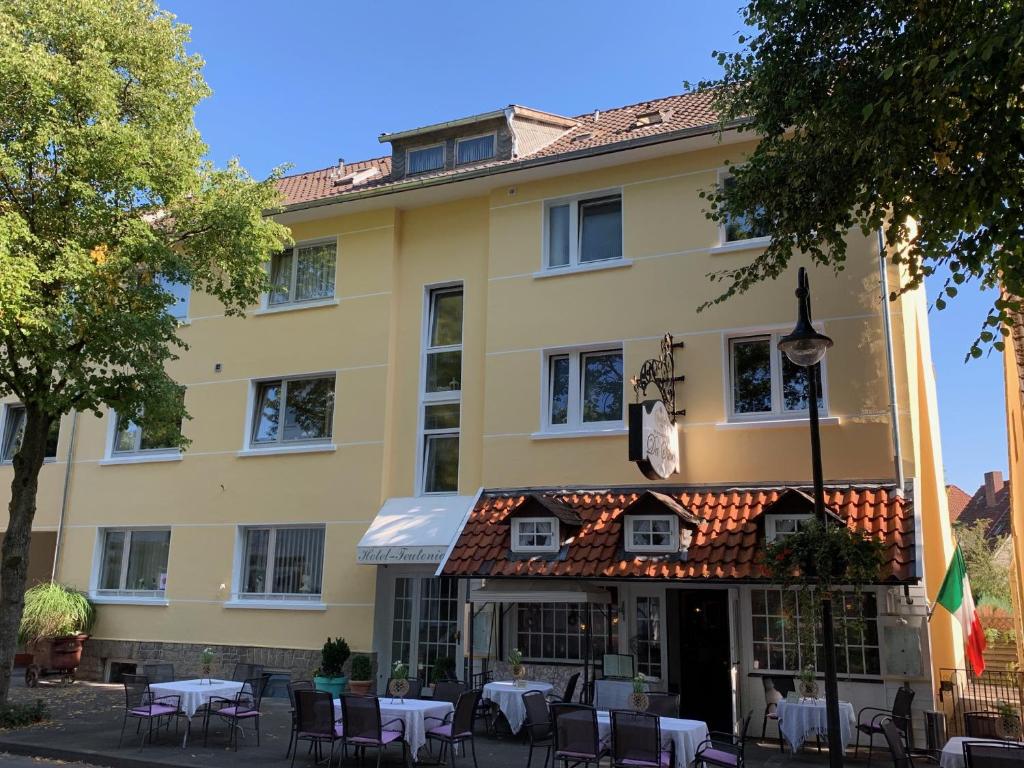 ein Gebäude mit Tischen und Stühlen davor in der Unterkunft Teutonia Hotel in Horn-Bad Meinberg