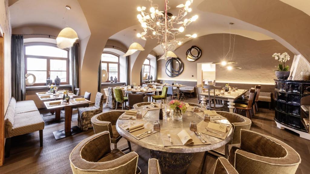 a restaurant with tables and chairs and a chandelier at Hotel Gasthof Fischer in Marchtrenk