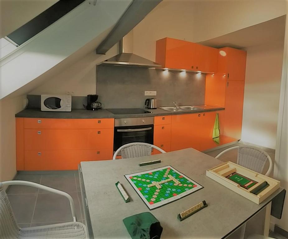 a kitchen with orange cabinets and a table with chairs at la Nichée in Hauteville-Lompnes