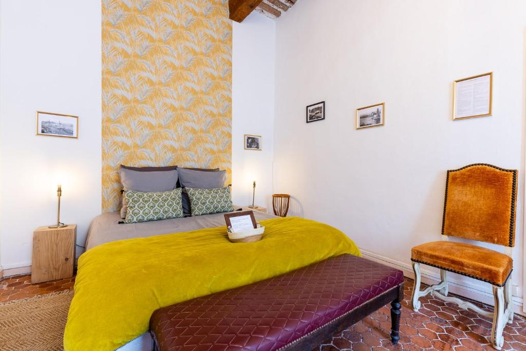 a bedroom with a bed with a yellow blanket and a chair at LE PANIER ENCHANTÉ - Suites & Loft - Terrasse et patio au dessus du Vieux Port in Marseille