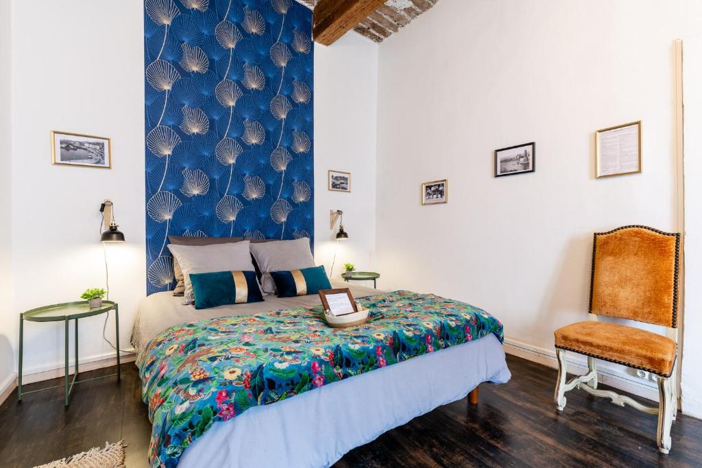 ein Schlafzimmer mit einem Bett und einem Stuhl in der Unterkunft LE PANIER ENCHANTÉ - Suites & Loft - Terrasse et patio au dessus du Vieux Port in Marseille