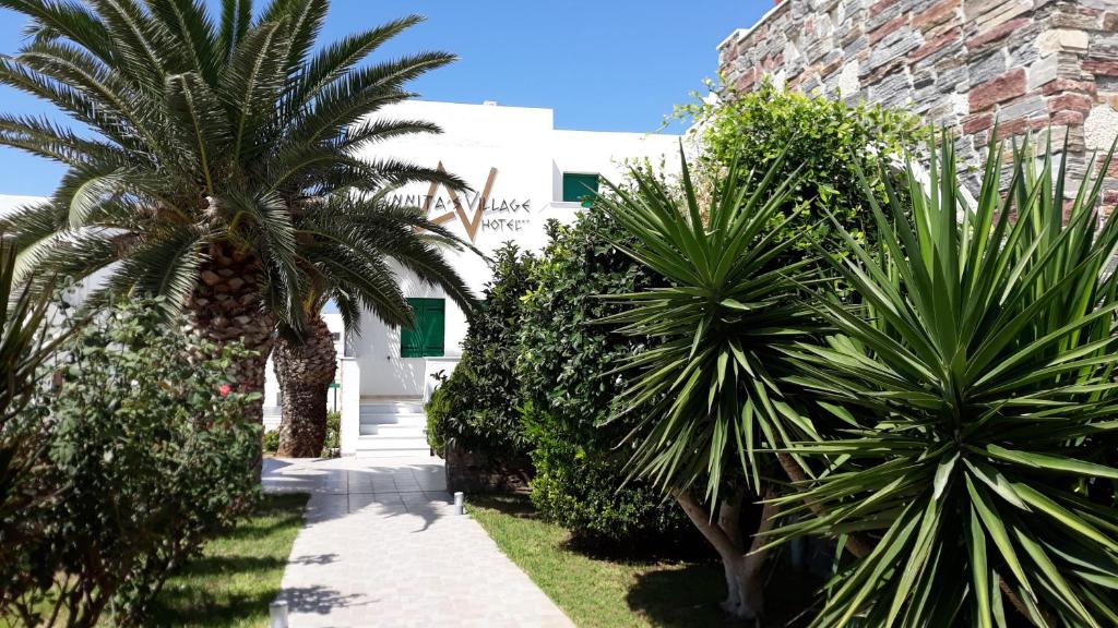 un patio con palmeras y un edificio blanco en Annita's Village Hotel, en Agia Anna de Naxos