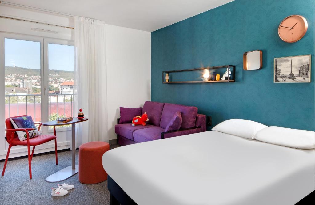 a hotel room with a bed and a couch at Hôtel ibis Styles Clermont-Ferrand Gare in Clermont-Ferrand