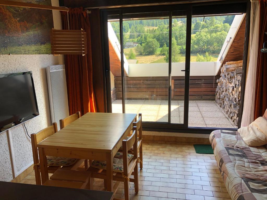 une salle à manger avec une table et une grande fenêtre dans l'établissement Duplex 6 à 8 couchages calme avec solarium plein Sud, à Ancelle