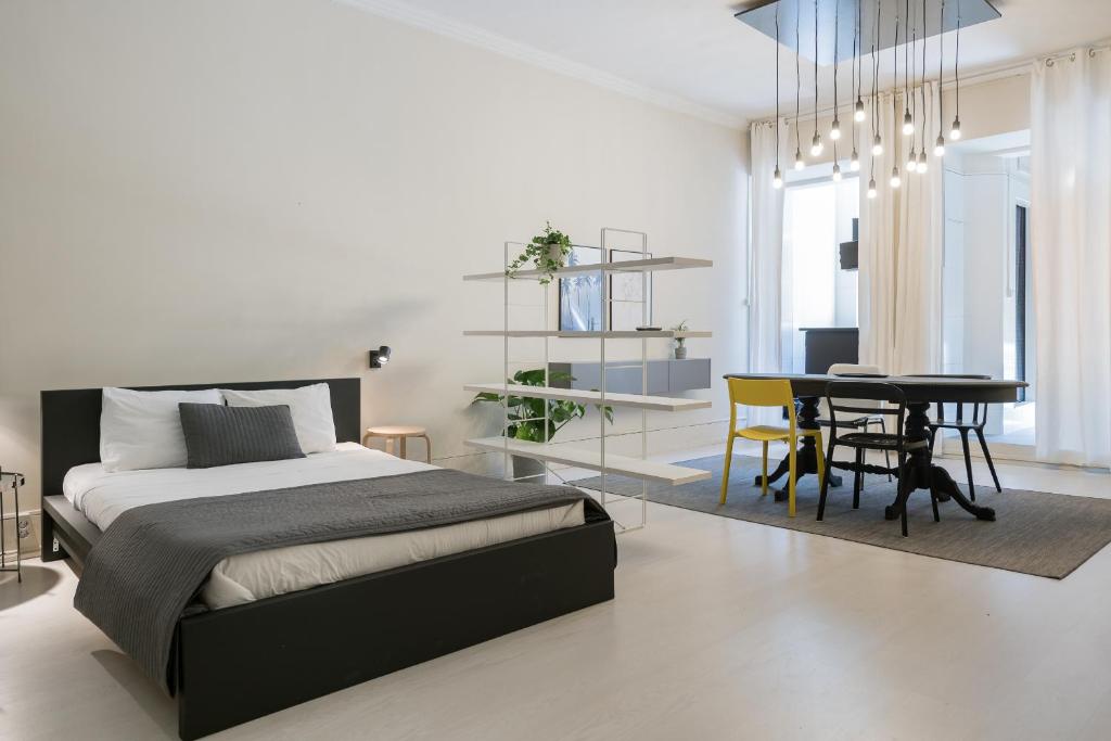 a bedroom with a bed and a dining room at Baixa24 •P1L• Amplo estúdio na baixa com varanda in Porto