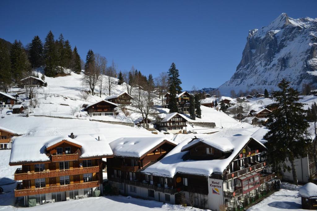 a building covered in snow with a mountain in the background at Hotel Caprice - Grindelwald in Grindelwald