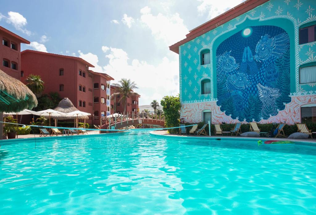 uma piscina num resort com um edifício azul em Selina Cancun Laguna Hotel Zone em Cancún