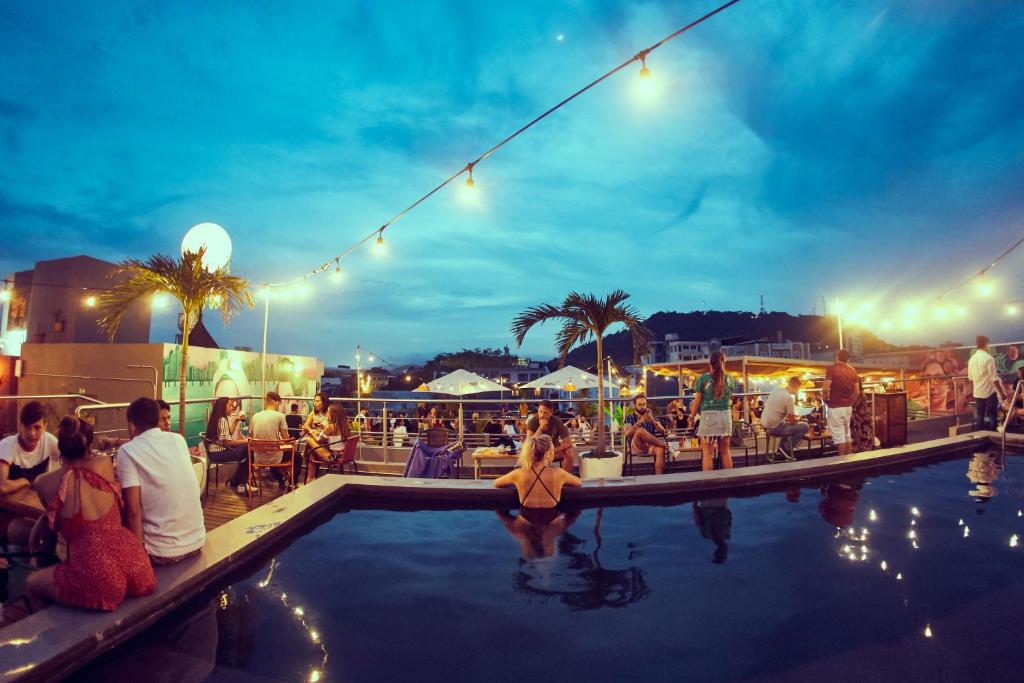 un groupe de personnes assises autour d'une piscine la nuit dans l'établissement Selina Casco Viejo Panama City, à Panama City