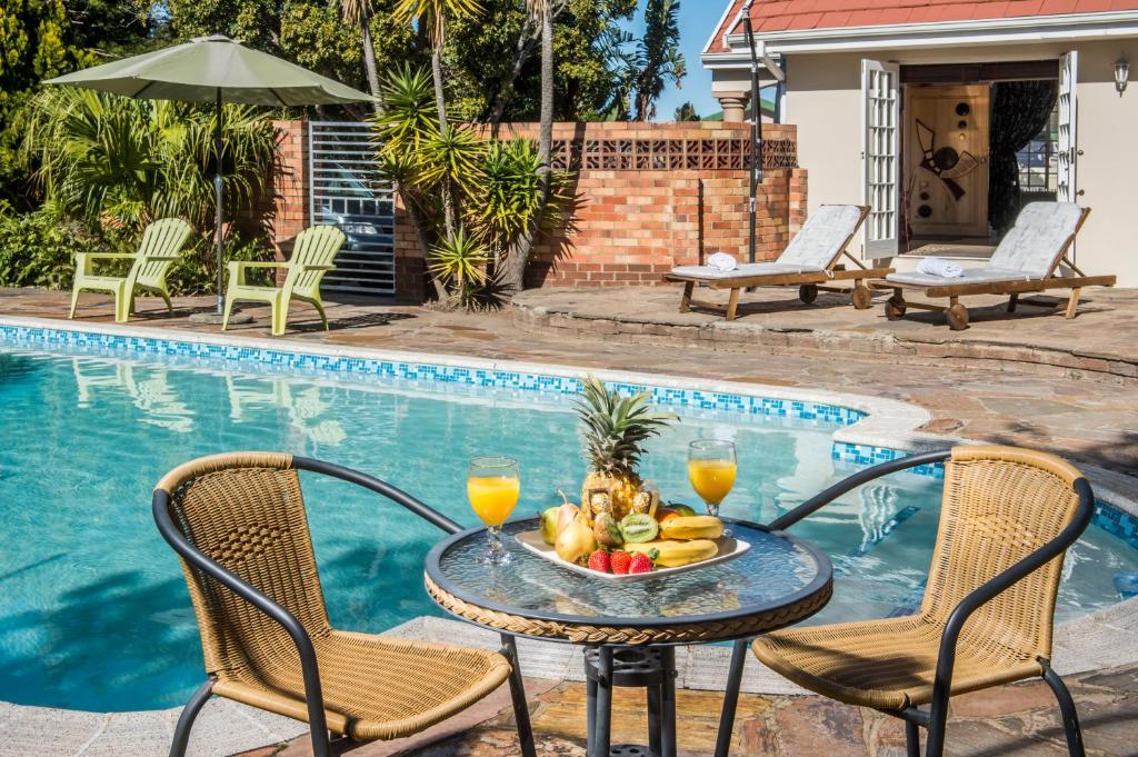 a table with fruit on it next to a swimming pool at Bhotani-on-Bax in Port Elizabeth
