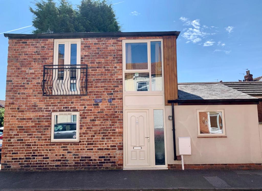 a brick house with a white door and a balcony at Detached one bedroom house near to castle and cathedral in Lincoln