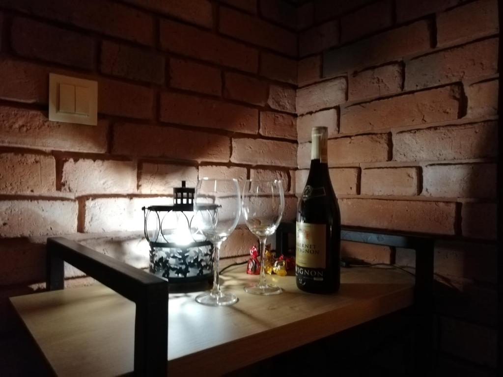 Una botella de vino y dos copas de vino en una mesa en Papaver Apartament, en Zielona Góra