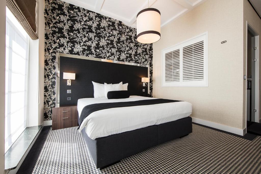 a bedroom with a large bed and a large window at Boutique Hotel Notting Hill in Amsterdam
