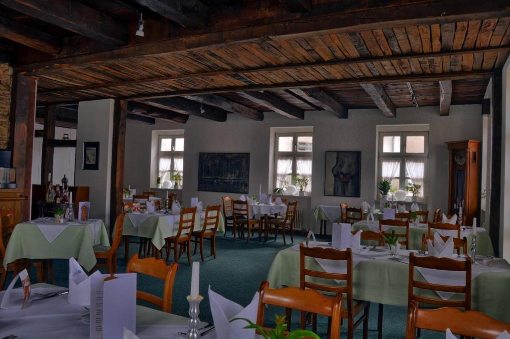 uma sala de jantar com mesas e cadeiras brancas em Hotel Alte Linden em Altena