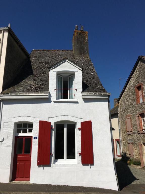 a white house with red doors and a window at Charming Cottage in a typical French Village in Saint-Christophe-du-Luat