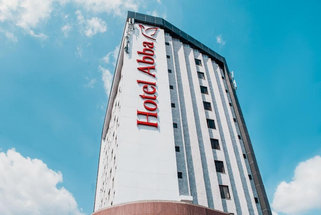 a tall white building with a red hotel sign on it at Abba Hotel in Betim