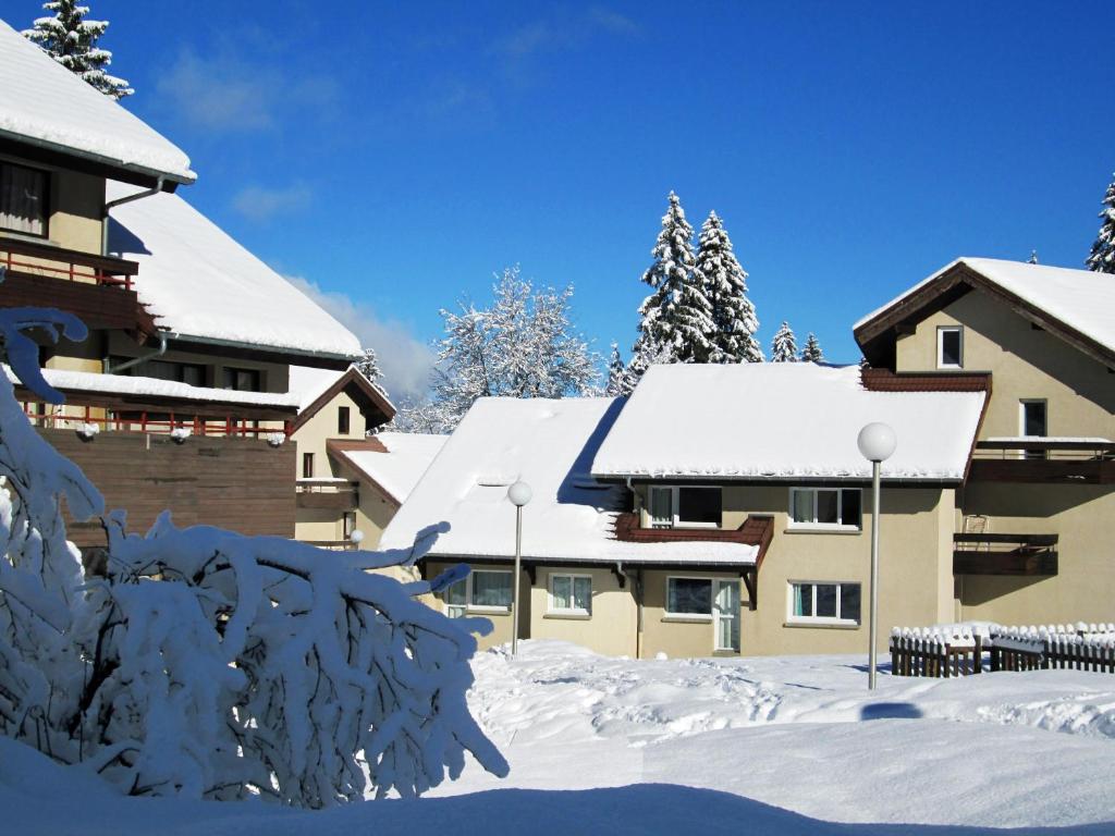 un bâtiment recouvert de neige avec des toits recouverts de neige dans l'établissement Village vacances du Haut-Bréda aux 7 Laux, à La Ferrière