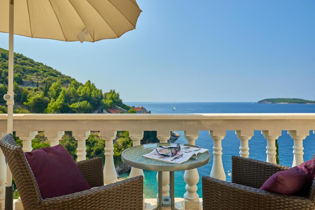 einen Balkon mit Stühlen, einem Sonnenschirm und dem Meer in der Unterkunft Hedera Estate, Hedera A53 in Dubrovnik