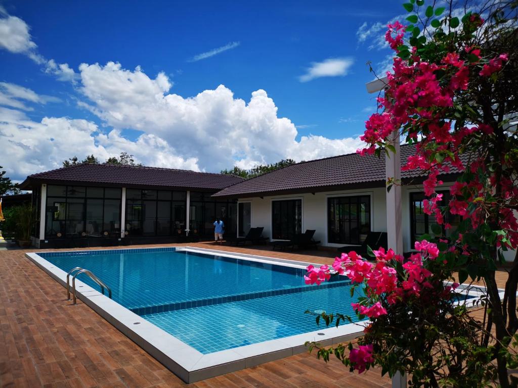 a swimming pool in front of a house with pink flowers at KK Garden 小院 in Hua Hin