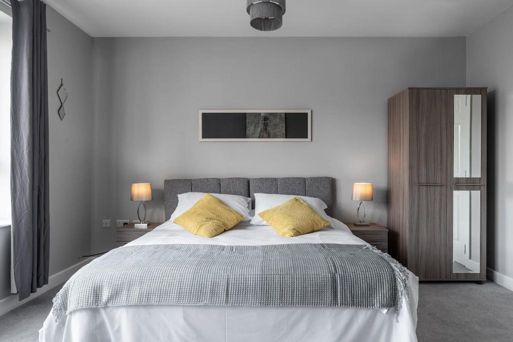 a white bedroom with a large bed with yellow pillows at Ashland House in Milton Keynes