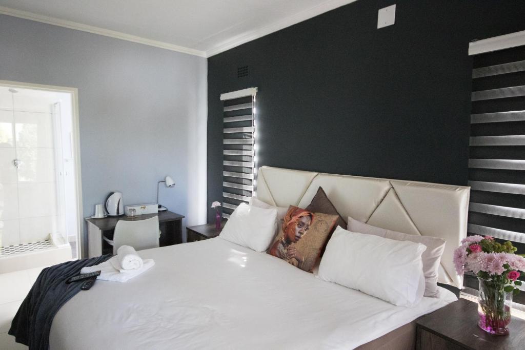 1 dormitorio con cama blanca y pared negra en 2 on ZK Matthews Guesthouse en Mthatha