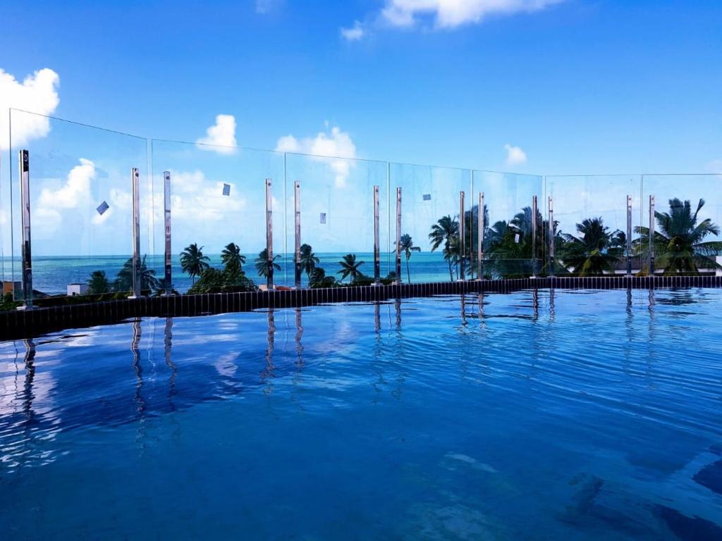 a large swimming pool with the ocean in the background at MAKAIBA FLATS De Luxo in Porto De Galinhas