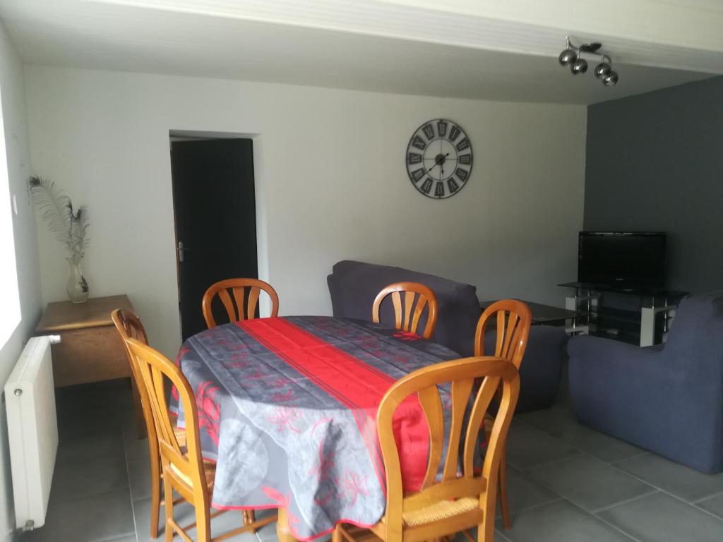 Un comedor con una mesa y sillas y un reloj. en Maison à la ferme, en Saint-Aubin-le-Monial