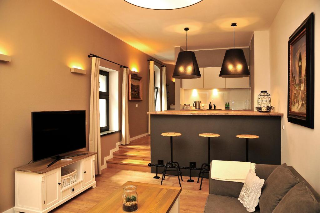 a living room with a television and a kitchen at Apartamenty Kopernika 14 in Toruń
