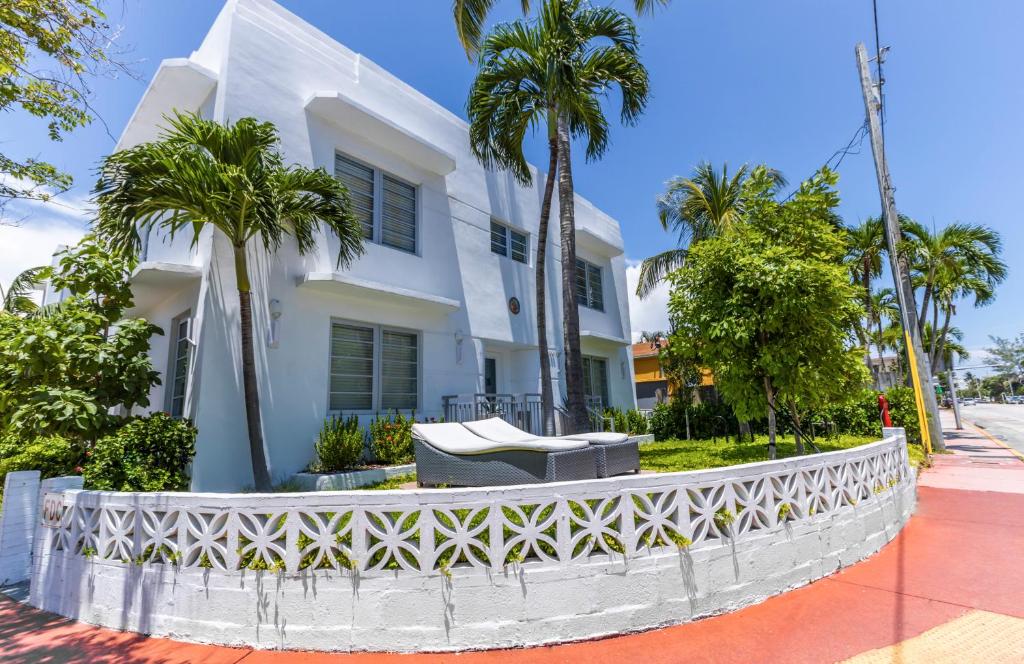 een wit gebouw met palmbomen ervoor bij Seaside All Suites Hotel in Miami Beach