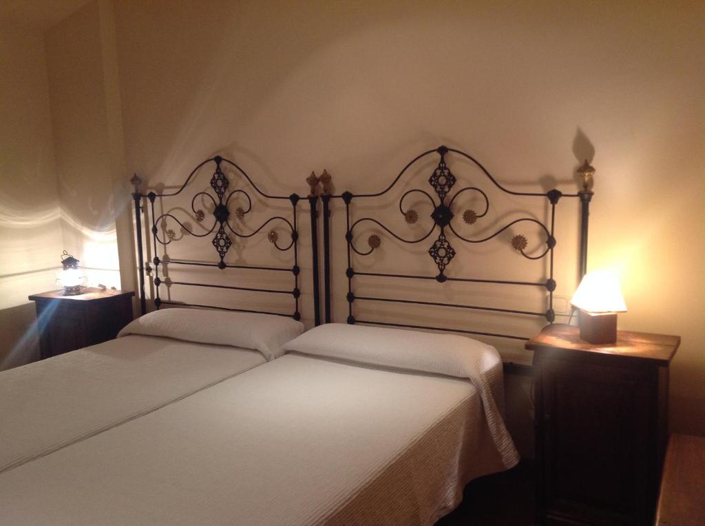 1 dormitorio con 2 camas blancas y 2 lámparas en Galican Casa Rural, en Moriscos
