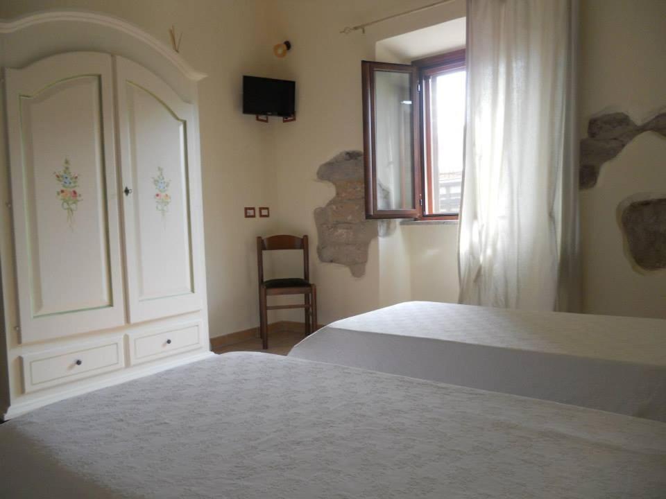 a bedroom with a bed and a dresser and a window at B&B Domu Delunas in Giba