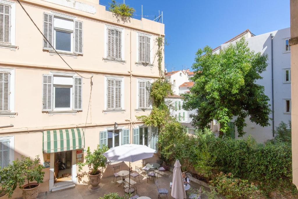 un edificio con sombrilla, sillas y un árbol en Forville, en Cannes