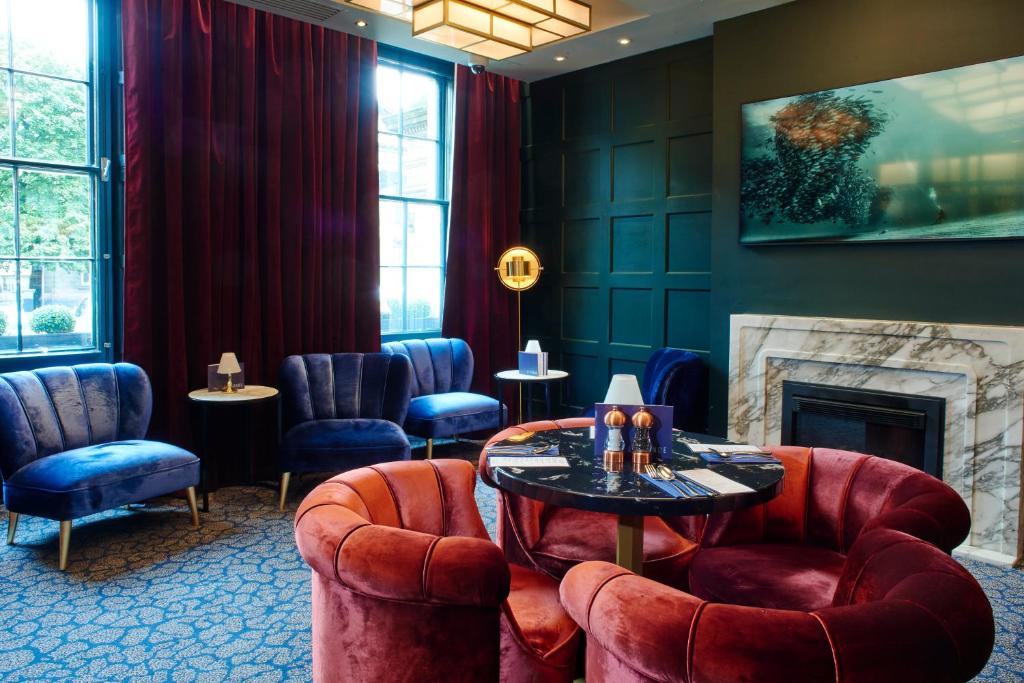 a waiting room with chairs and a table and a fireplace at Le Monde Hotel in Edinburgh