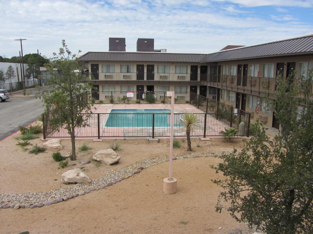 a building with a swimming pool in front of it at Howard Johnson by Wyndham Odessa TX in Odessa