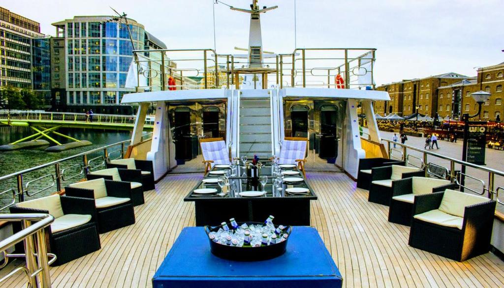a deck of a boat with a table and chairs at Absolute Pleasure Yacht in London