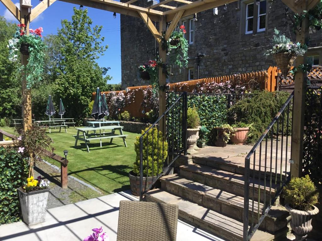 a garden with stairs and a pergola and a bench at Blenkinsopp Castle Inn in Greenhead