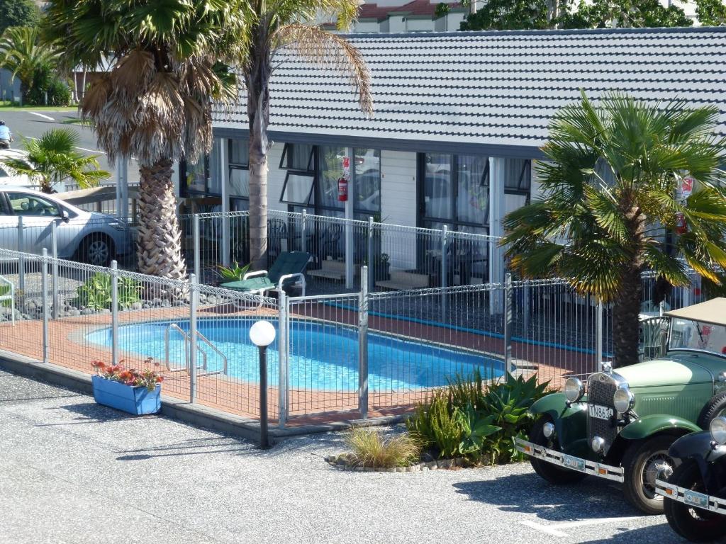 una valla alrededor de una piscina frente a una casa en Mana-Nui Motel en Whitianga