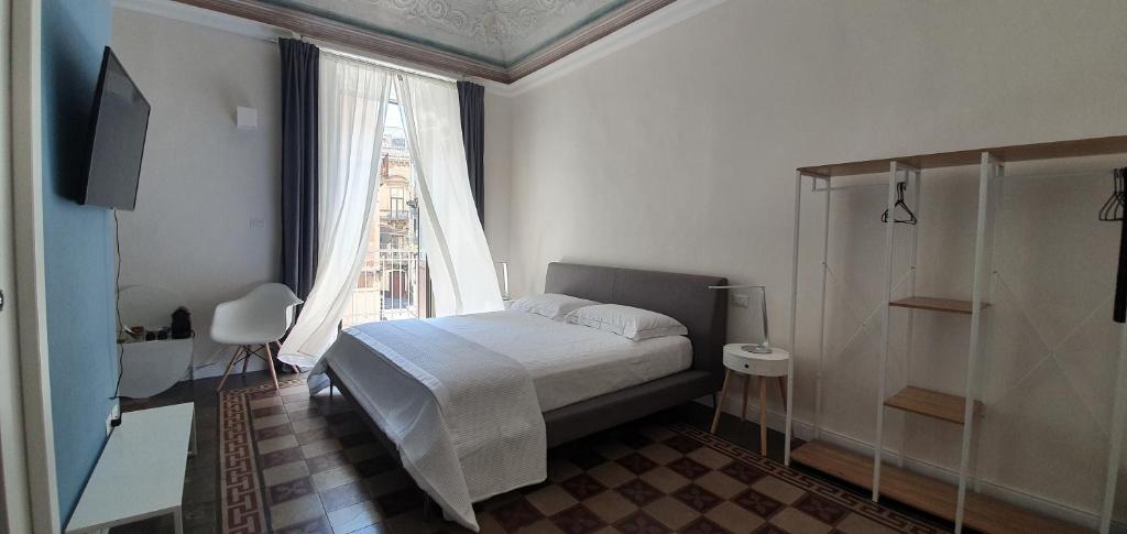 une chambre avec un lit et une grande fenêtre dans l'établissement Palazzo del Verga, à Catane