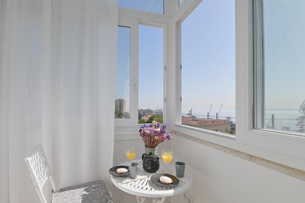 a white table with a vase of flowers and two windows at MyPlaceLisbon - Tágides River View in Lisbon