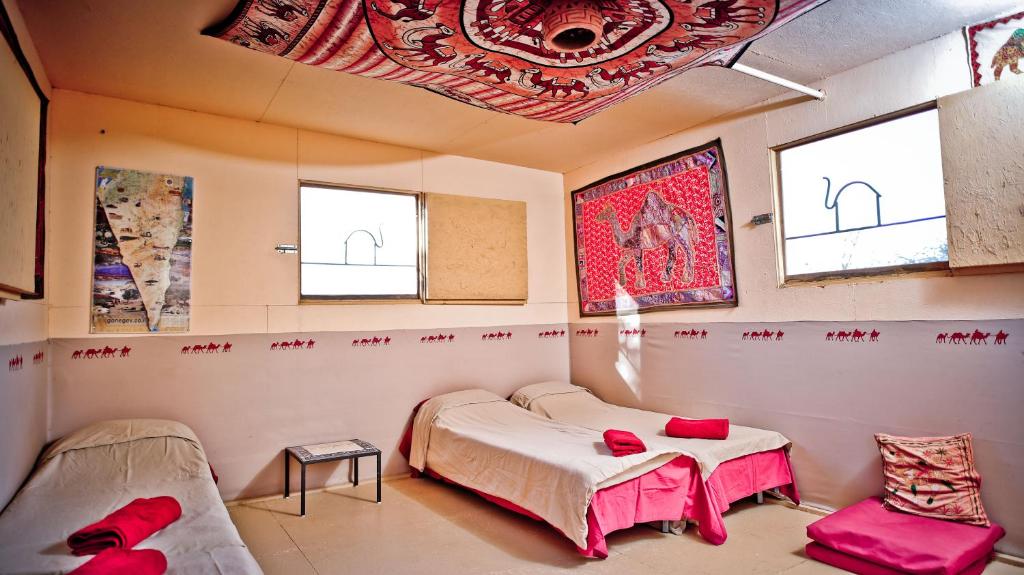 a room with two beds and a table and windows at Negev Camel Ranch in Dimona