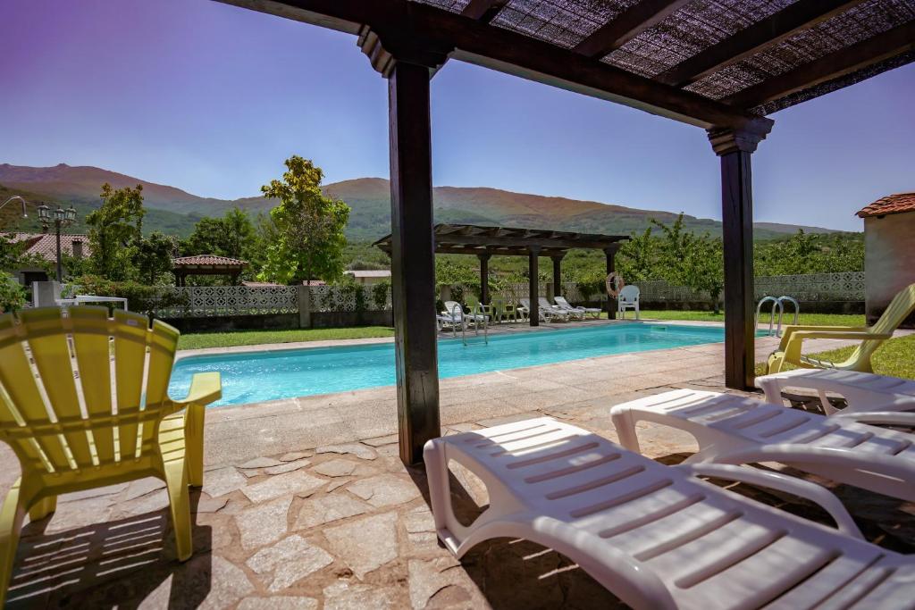 a group of lawn chairs sitting next to a swimming pool at La Cañada del Valle del Jerte in Navaconcejo