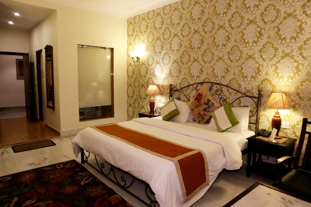 a bedroom with a large bed and a large mirror at Suryaa Villa - A Boutique Heritage Hotel in Jaipur