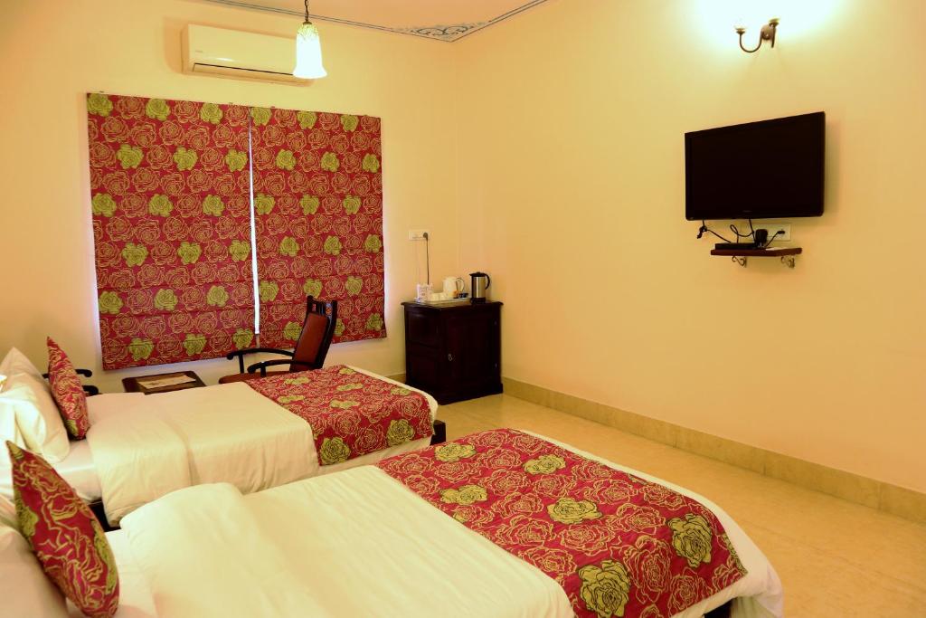 a hotel room with two beds and a flat screen tv at Suryaa Villa - A Boutique Heritage Hotel in Jaipur
