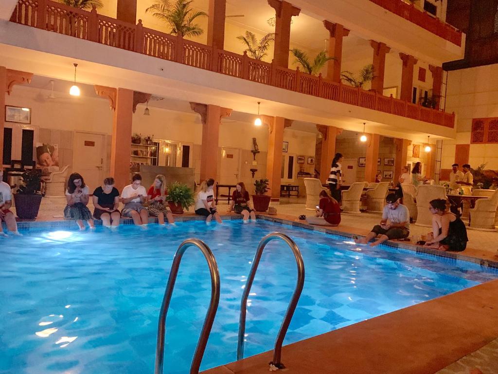 a group of people sitting around a swimming pool at Suryaa Villa - A Boutique Heritage Hotel in Jaipur