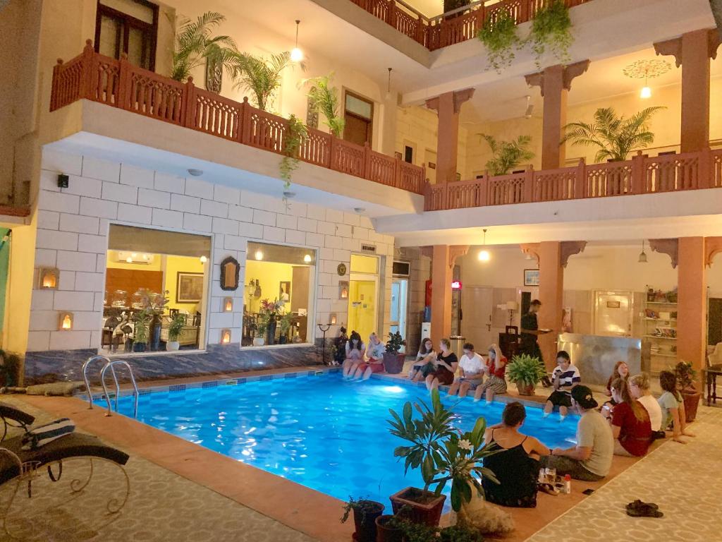a group of people sitting around a swimming pool at Suryaa Villa - A Boutique Heritage Hotel in Jaipur