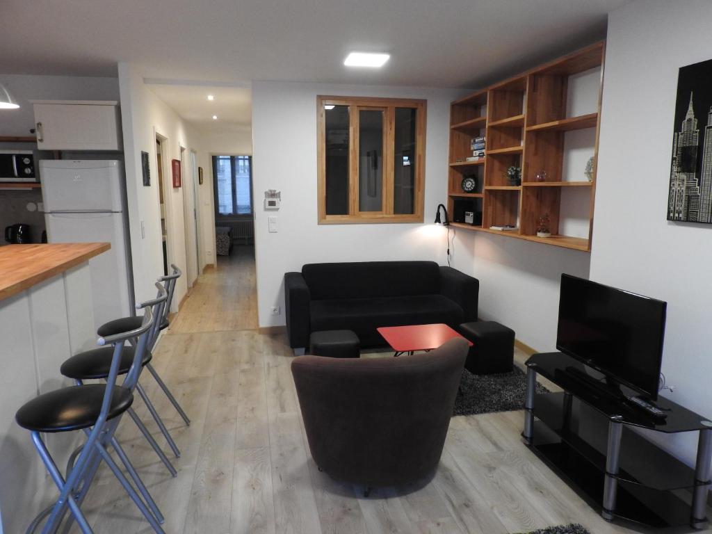 ein Wohnzimmer mit einem schwarzen Sofa und Stühlen in der Unterkunft Appartement hyper centre ville au calme in Besançon