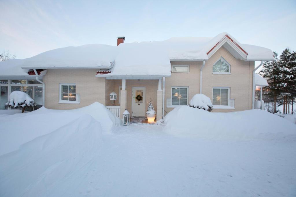 uma casa coberta de neve em frente dela em Villa Ranta em Rovaniemi