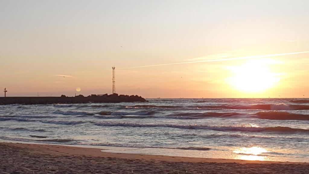 a sunset on the beach with the sun setting at Guest House Gero Vėjo Namai in Klaipėda